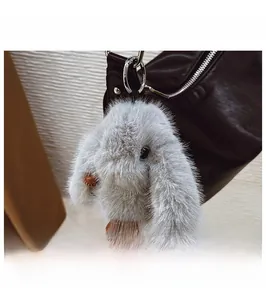 Close-up of a fluffy grey rabbit plush charm with brown faux leather paws on a black bag
