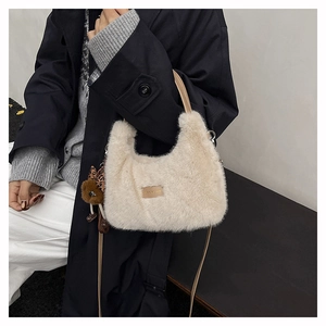 Detail of plush off-white faux fur handbag with a brown bear charm and leather strap