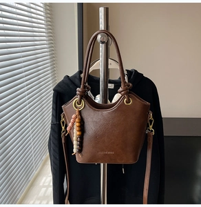 Detail of dark brown leather bucket bag with retro hardware and beaded tassel charm