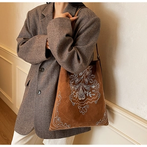Nahaufnahme der braunen Wildledertasche mit kunstvollen weißen Blumenstickereien