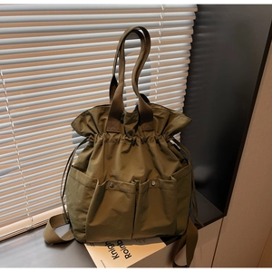 Detailed view of army green nylon bucket bag with three snap pockets and drawstring closure