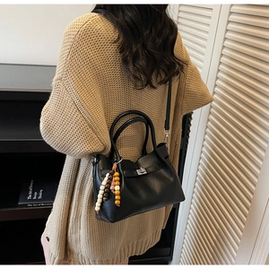 Détail du sac seau en cuir noir texturé avec breloque perlée et fermoir argenté