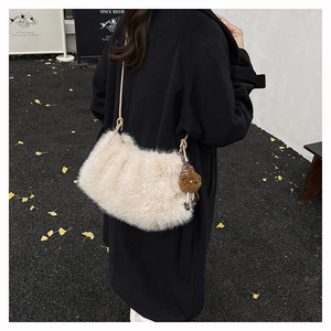 Detail of plush faux fur shoulder bag in cream white with cute teddy bear charm