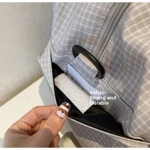Detail der grauen Reisetasche mit Karomuster und Seitentasche mit Klettverschluss