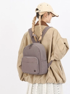 Minimalist grey nylon backpack for women featuring waterproof fabric and metallic logo detail