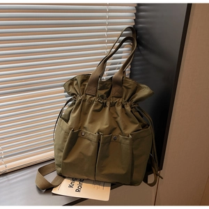 Detail view of olive green drawstring bucket bag showing front pockets and cargo texture