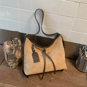 Detail view of khaki suede crescent bag with dark brown leather trim and drawstring tie