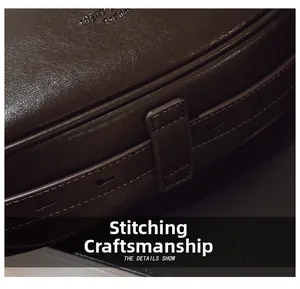 Macro shot of dark brown leather stitching detail and adjustable strap on saddle bag