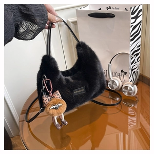 Close-up of black fuzzy plush handbag with bear charm and leopard bow on brown table