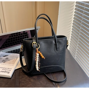 Detail of black matte leather mini tote bag with wood bead charm and embossed logo