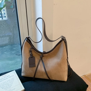 Detail of a brown suede hobo bag featuring leather trim and vintage drawstring elements