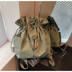 Detail of army green canvas bucket bag featuring metallic snap pockets and drawstring closure