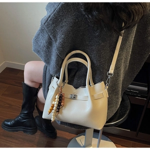 Détail du sac seau en cuir blanc crème avec fermoir argenté et charm en perles de bois