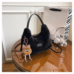 Detail of plush hobo bag with 'love every day' label and cute plush charm on a desk