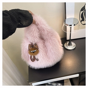 Dettaglio della borsa in ecopelliccia rosa con pendente a macchia e pompon alla moda