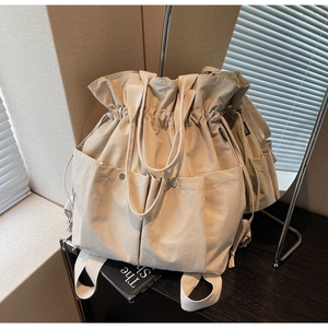 Detail of beige canvas bucket bag with drawstring closure and metal snap pockets
