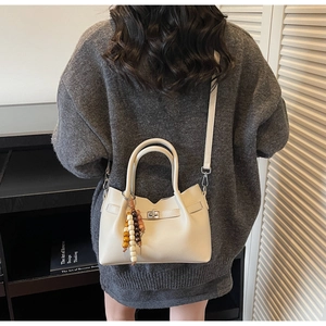 Sac seau chic crème avec texture litchi et charmant pompon en perles colorées