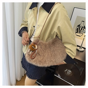 Furry brown shoulder bag with plush texture and decorative pom-pom on female model