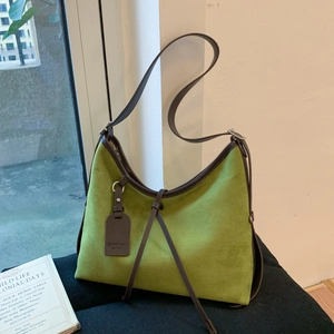 Detail view of avocado green frosted leather bag with vintage texture and dark brown strap