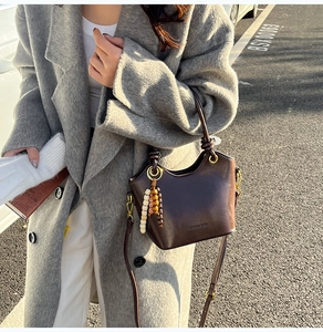 Outdoor lifestyle shot of a dark brown retro leather bucket bag with beaded accessory