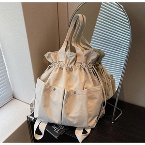 Detail of beige canvas bucket bag with drawstring closure and metal snap pockets