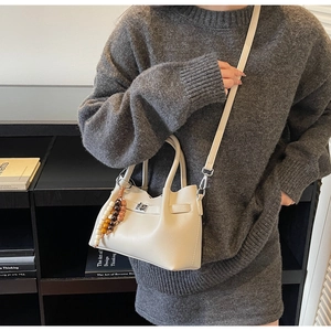 Détail du sac seau crème avec texture grainée et breloque bohème en perles