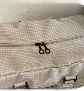 Detailansicht des glatten Doppelreißverschlusses an der karierten Reisetasche in Beige