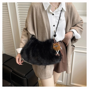 Detail of black faux fur shoulder bag with soft plush texture and cute monster charm