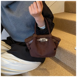 Detail of a brown fuzzy bucket bag featuring a silver twist lock and faux fur trim