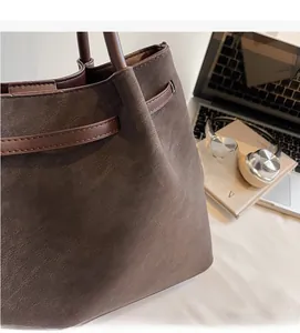 Close-up of large coffee brown suede tote bag with decorative leather straps for work