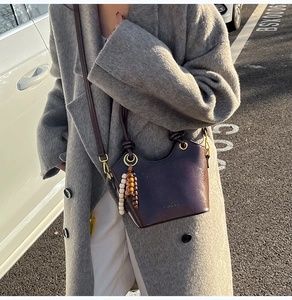 Detail of vintage dark brown bucket bag with smooth oil-wax finish and wooden bead charm