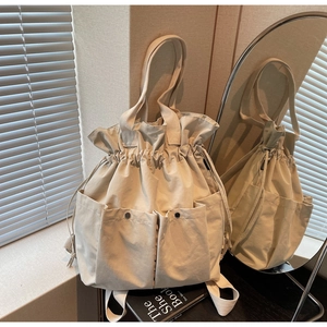 Detail view of beige drawstring bucket bag with large snap pockets and fabric texture