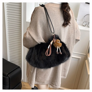 Detail of black faux fur shoulder bag with plush charm and leopard bow on model