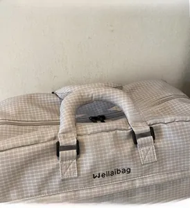 Nahaufnahme der grauen Reisetasche mit Karomuster, Markenlogo und verstärktem Griff