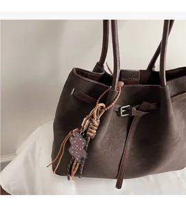 Detail of dark brown leather tote bag featuring a decorative beaded leopard print pendant