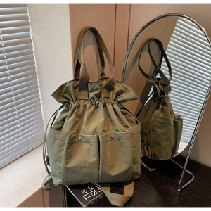 Detail view of olive green drawstring bucket bag with silver snaps and woven handles