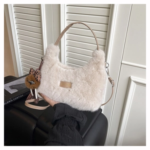 Detail of beige faux fur handbag with leopard bow charm and brown leather handles