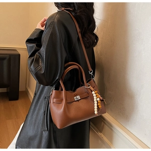 Détail du sac en cuir marron grainé avec fermoir argenté et breloque en perles