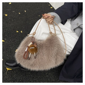 Close-up of a plush crescent shoulder bag with a cute brown fur ball charm