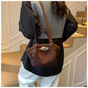 Detail of dark brown suede bucket bag with shearling trim and silver metal twist lock