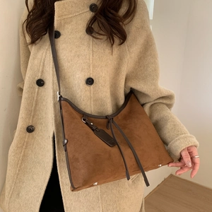 Detail of vintage brown suede shoulder bag with leather piping and metal studs on base