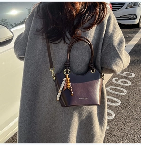 Detail of vintage dark brown faux leather bucket bag with unique beaded charm pendant