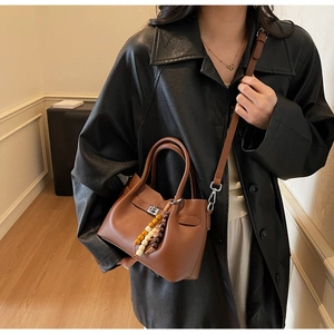 Détail d'un sac seau en cuir marron avec fermoir rotatif argenté et breloque perlée