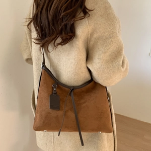 Detailed back view of a brown suede hobo bag with leather trim on model