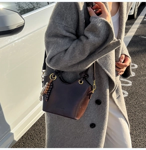 Detail view of a vintage dark brown leather bucket bag with a golden ring and beads