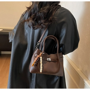 Détail d'un sac seau marron avec ornement de perles sur un manteau noir élégant