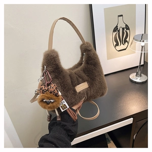 Detail of soft brown faux fur handbag with leather strap and cute plush doll pendant