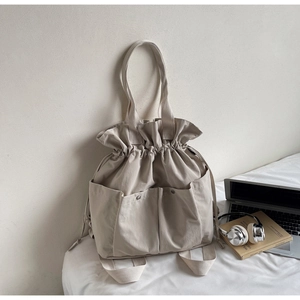 Detail of beige canvas bucket bag featuring drawstring closure and functional front pockets
