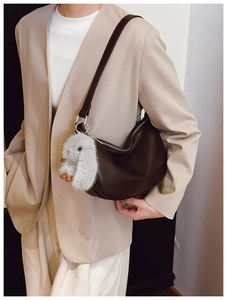 Detail of dark brown leather hobo bag with long strap and grey plush rabbit charm