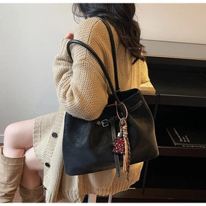 Close-up of black leather tote bag featuring a cute leopard print bear charm accessory